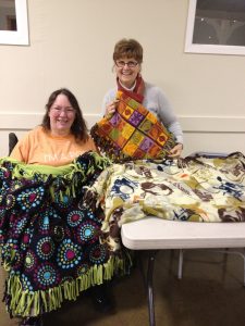 Smiling volunteers with the blanket they made